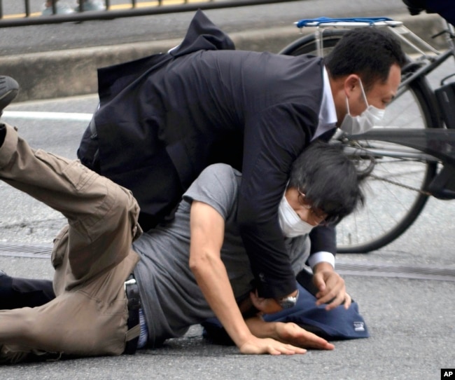 Tetsuya Yamagami, bottom, is detained near the site of gunshots in Nara Prefecture, western Japan, July 8, 2022. (Katsuhiko Hirano/The Yomiuri Shimbun via AP)