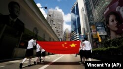 Pelajar membawa bendera nasional China selama parade di jalan pusat kota Hong Kong untuk merayakan ulang tahun ke-12 penyerahan Hong Kong ke China, Rabu, 1 Juli 2009. (Foto: AP/Vincent Yu)