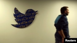 FILE - An employee walks past a Twitter logo made from California license plates at the company's headquarters in San Francisco, California October 4, 2013. (REUTERS/Robert Galbraith/File Photo)