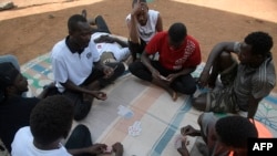 Un demandeur d'asile soudanais joue au poker devant des maisons temporaires au centre de transit d'urgence de Gashora à Gashora, au Rwanda, le 25 juin 2022.