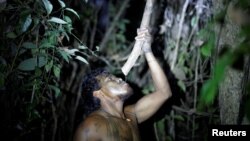 FILE - Indigenous leader Paulo Paulino Guajajara drinks water from a tree branch at a makeshift camp on Arariboia indigenous land near the city of Amarante, Maranhao state, Brazil, September 10, 2019.