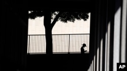 In this file photo, a person is silhouetted against a wall as they look down at their cell phone outside the Clara Shortridge Foltz Criminal Justice Center on July 29, 2021, in Los Angeles, California. (AP Photo/Chris Pizzello, File)