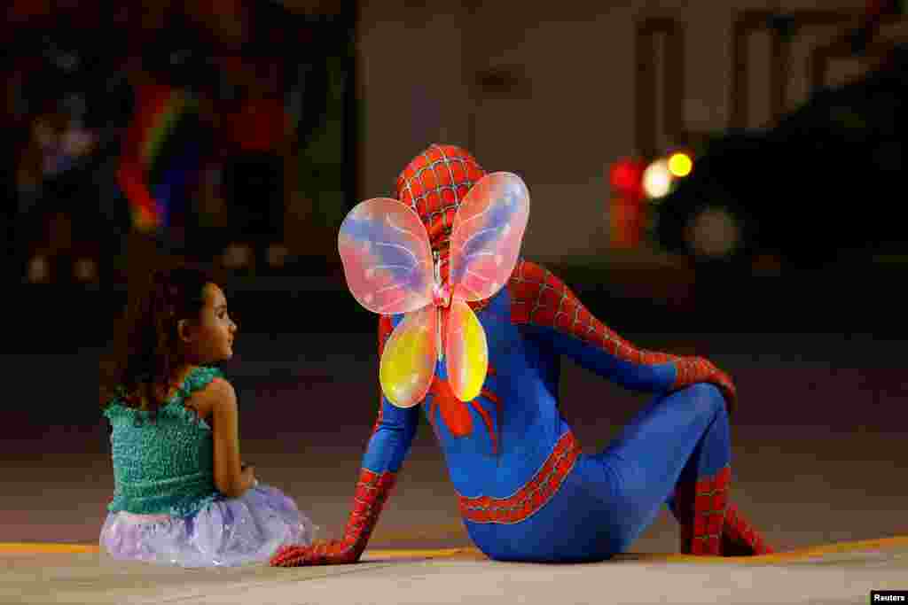 Genesis, 4, looks at a person wearing a costume of Spider-Man with butterfly wings, as they attend a march of the LGBT+ pride celebrations, in Ciudad Juarez, Mexico, June 19, 2022.