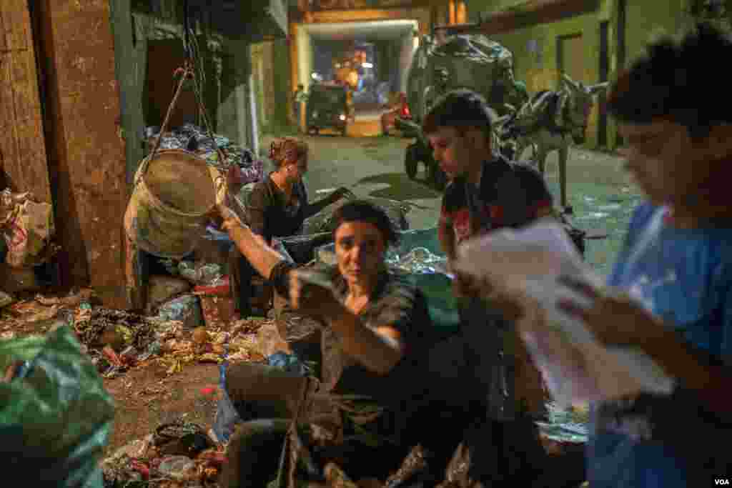 After finishing work at the rug factory, Omu Abanoub joins her family to recycle trash for extra income, in east Cairo, June 26, 2022. 