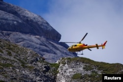 A helicopter participates in search and rescue operations at the site of a deadly collapse of parts of a mountain glacier in the Italian Alps, at the Dolomites' Marmolada ridge, Italy, July 5, 2022. (REUTERS/Guglielmo Mangiapane )
