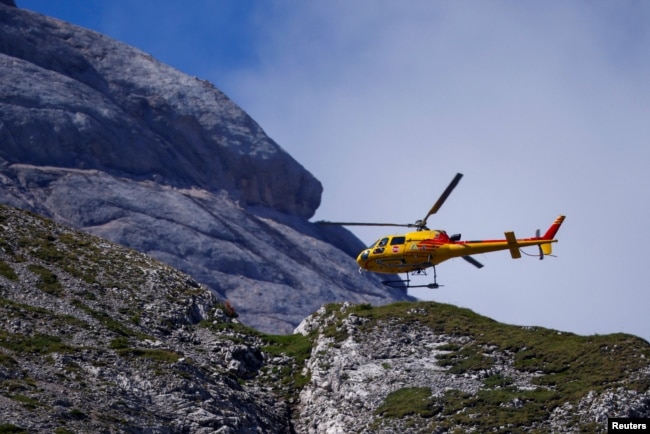 A helicopter participates in search and rescue operations at the site of a deadly collapse of parts of a mountain glacier in the Italian Alps, at the Dolomites' Marmolada ridge, Italy, July 5, 2022. (REUTERS/Guglielmo Mangiapane )