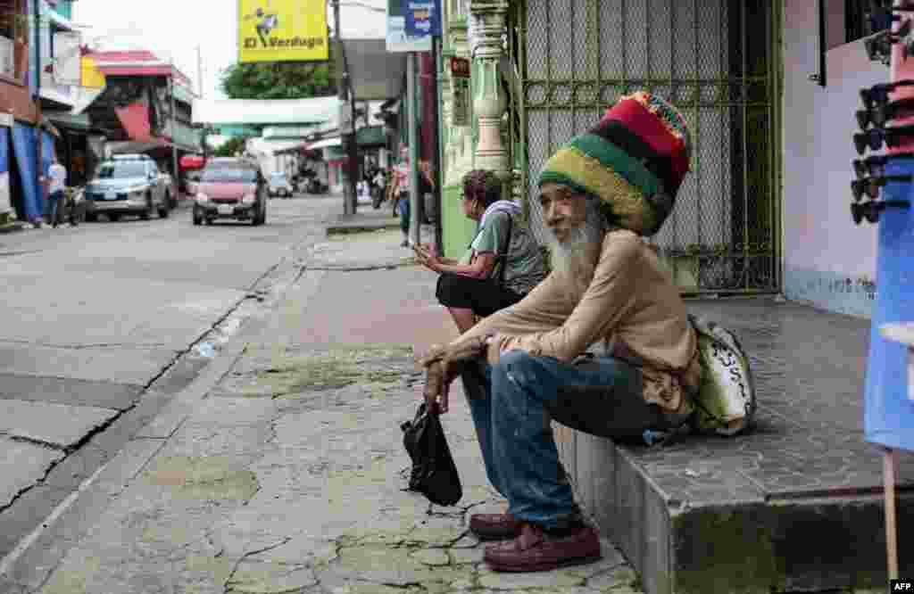 Un residente se sienta en una calle cerca de un mercado. Los nicaraguenses aseguran sus propiedades y pertenencias y compran algunos viveres mientras esperan por la tormenta.&nbsp;