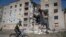 A man rides a bicycle past a building damaged in Russian shelling in Bakhmut, Donetsk region, Ukraine, Monday, June 20, 2022. 