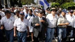 ARCHIVO - El Coronel retirado Sigifredo Ochoa Pérez, centro vistiendo traje, camina con sus partidarios a las oficinas de los altos mandos del ejército para pedir la baja del servicio activo en San Salvador, El Salvador, en enero de 2012.