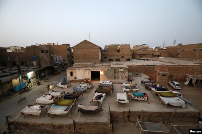 Men sleep on charpoy rope beds, early in the morning during a heatwave, on a roof in Jacobabad, Pakistan, May 15, 2022. (REUTERS/Akhtar Soomro)