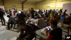 Migrantes esperan en un almacén administrado por el grupo sin fines de lucro Mission: Border Hope, en Eagle Pass, Texas, el 23 de mayo de 2022. La Patrulla Fronteriza libera hasta 1,000 migrantes diariamente en Mission: Border Hope. El grupo sin fines de lucro, dirigido por la Iglesia Metodista Unida, se mudó al almacén en abril en medio de la práctica de la administración Biden de liberar a los migrantes con libertad condicional. (Foto AP/Dario López-Mills)