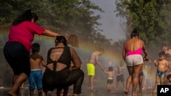 FILE - Children and adults cool off in a fountain in a park by the river in Madrid, Spain, June 17, 2022.