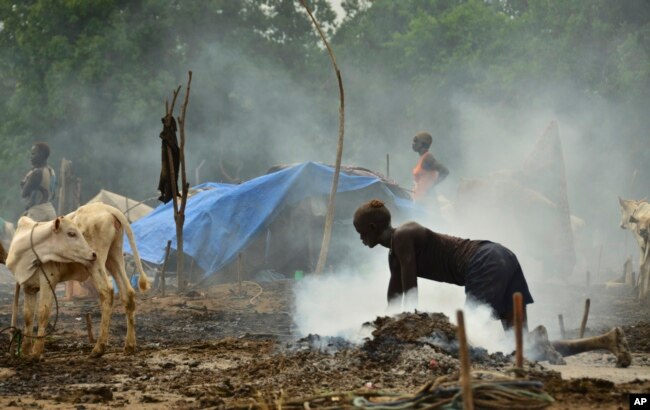 FILE - In this photo taken Monday, July 31, 2017, a young South Sudanese woman scrubs the dung-covered ground in preparation for cows to return from grazing outside the town of Rumbek, South Sudan. (AP Photo/Mariah Quesada)