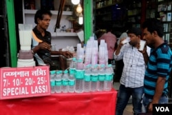 A shopkeeper is selling sweetened yogurt drinks using single-use plastic glasses, near a railway station in Kolkata. (Shaikh Azizur Rahman/VOA)