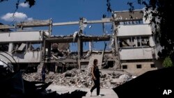 ইউক্রেনীয় সাংবাদিকরা খারকিভে রুশ হামলায় ধ্বংসপ্রাপ্ত ন্যাশনাল পেডাগোজিক ইউনিভার্সিটির উঠোনে হাঁটছেন। ৬ জুলাই, ২০২২।