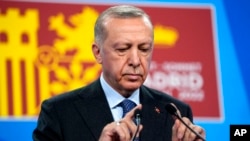 Turkish President Recep Tayyip Erdogan tests the microphone prior to addressing a media conference at a NATO summit in Madrid, June 30, 2022. 