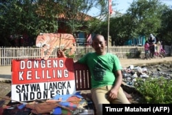 Mantan guru Samsudin berpose dengan boneka kardus saat mengajar anak-anak tentang konservasi satwa di Desa Cemara Kulon, Indramayu. (Foto: AFP/Timur Matahari)