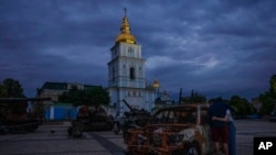 A couple look at destroyed Russian tanks installed as a symbol of war in front of St. Michael cathedral, in Kyiv, Ukraine, June 23, 2022.