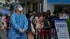 A worker in protective gears reacts as residents line up at a testing site due to requirements for a negative COVID test in the last 72 hours to enter some buildings and using public transportation in Beijing, China, July 4, 2022. 