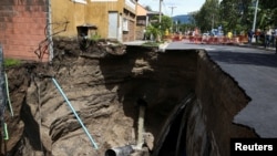 Los trabajadores se paran junto a una calle colapsada después de una inundación causada por fuertes lluvias, después de la tormenta tropical Bonnie, en San Salvador, El Salvador, 3 de julio de 2022. REUTERS/José cabezas