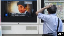 A man looks at a television broadcast showing news about the fatal attack on former Japanese prime minister Shinzo Abe, along a street of Tokyo.