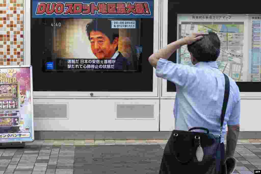 A man looks at a television broadcast showing news about the fatal attack on former Japanese prime minister Shinzo Abe, along a street of Tokyo.