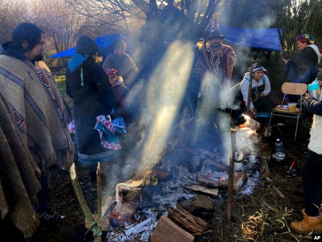 Members of the Mapuche Indigenous community gather while cooking a barbecue during celebrations of the Wetripantu or Mapuche New Year, in Corrayen village, Puyehue district, Chile, in this Tuesday, June 21, 2022 iPhone photo, taken by Rodrigo Abd. (AP Photo/Rodrigo Abd)