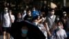 People wearing face masks walk across a crosswalk in the central business district in Beijing, June 24, 2022.