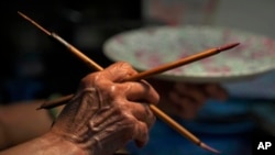 A staff member works at the Yuet Tung China Works, Hong Kong's last hand-painted porcelain factory, in Hong Kong, June 8, 2022.