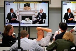 Wartawan menonton di layar TV pertemuan Presiden Rusia Vladimir Putin dan Presiden Joko Widodo di Kremlin di Moskow, 30 Juni 2022. (Foto: AP)