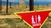 FILE - An international sign warning about mines hangs beside a minefield at Bagram Air Base on, March 22, 2002.