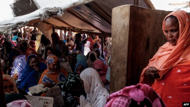 FILE - Malian refugees wait outside a food distribution center in M'Berra camp in South East Mauritania for their allocation of food assistance in Bassikounou on June 7, 2022.