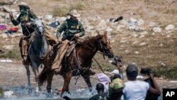 ARCHIVO - Agentes estadounidenses de la Patrulla Fronteriza montados a caballo intentan contener el 19 de septiembre de 2021 a los migrantes mientras cruzan el río Bravo desde Ciudad Acuña, México, hacia Del Rio, Texas. Foto AP.