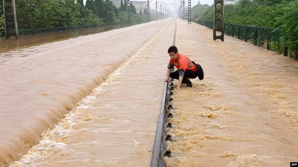 中国江西上饶一名铁路工人在暴雨后检查被洪水淹没的铁轨情况。（2022年6月21日）(photo:VOA)