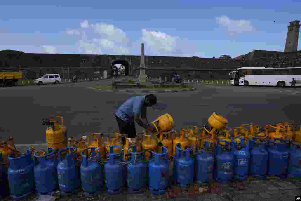 A man uses a padlock to secure his empty cooking gas canister placed in a queue expecting government supply in Galle, Sri Lanka.