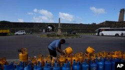A man uses a padlock to secure his empty cooking gas canister placed in a queue expecting government supply in Galle, Sri Lanka.