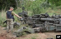FILE - A Ukrainian soldier stands by a U.S.-supplied M777 howitzer in Ukraine's eastern Donetsk region, June 18, 2022.