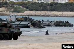 FILE - Spanish Navy soldiers disembark armored vehicles onto a beach during the FLOTEX-22 exercise organized by the Spanish Navy at a naval base in Rota, Spain, June 15, 2022.