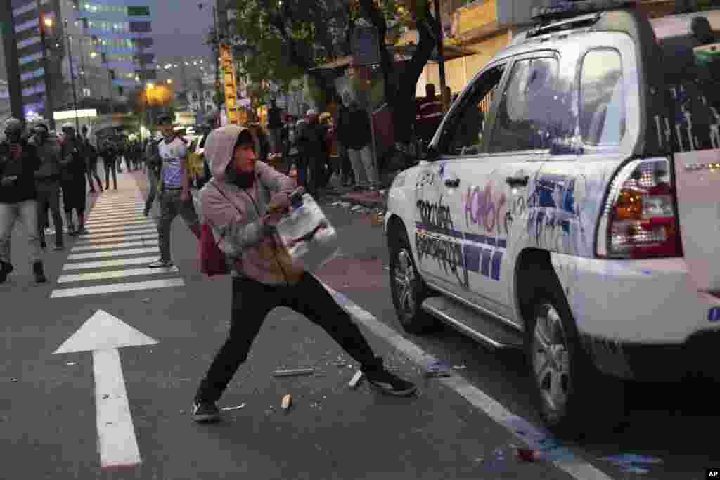 Un joven destroza un carro policial frente a la Unidad de Flagrancia de la Fiscalía durante una protesta exigiendo la libertad del líder indígena Leonidas Iza, en Quito. Ecuador, el martes 14 de junio de 2022. (Foto AP/Dolores Ochoa)