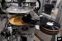 Freshly pressed vinyl records are produced in a stamper at the United Record Pressing facility Thursday, June 23, 2022, in Nashville, Tenn. (AP Photo/Mark Humphrey)