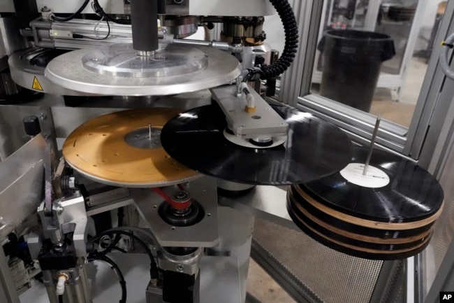 Freshly pressed vinyl records are produced in a stamper at the United Record Pressing facility Thursday, June 23, 2022, in Nashville, Tenn. (AP Photo/Mark Humphrey)
