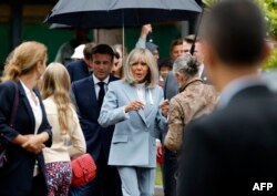 Presiden Prancis Emmanuel Macron (tengah, kiri) bersama istrinya Brigitte Macron (tengah, kanan) seusai memberikan suara di TPS Le Touquet, Prancis utara, 19 Juni 2022. (Ludovic MARIN / AFP)