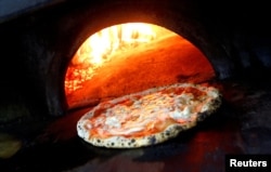 Pizza Margherita sedang dimasak dalam oven berbahan bakar kayu di L'Antica Pizzeria da Michele di Naples, Italia, 6 Desember 2017. (Foto: Reuters)