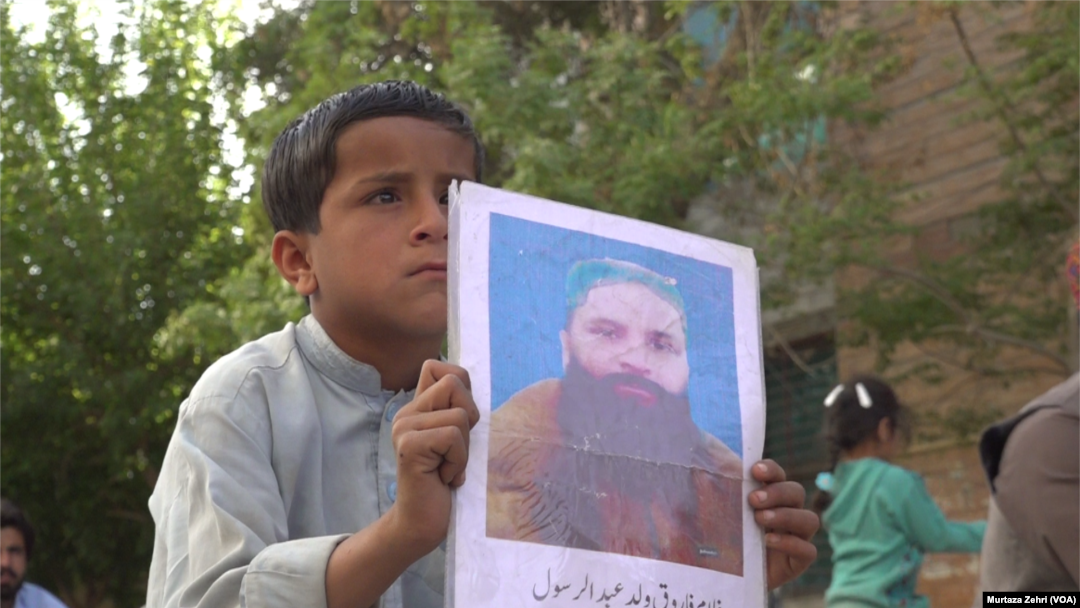 لاپتا افراد کی بازیابی کا مطالبہ کرنے والے ایک بچے نے اپنے رشتہ دار کی تصویر اٹھا رکھی ہے۔(فائل فوٹو)