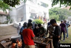 People cook in the garden of the Prime Minister's residence on the following day after demonstrators entered the building, amid the country's economic crisis, in Colombo, Sri Lanka July 10, 2022. (REUTERS/Dinuka Liyanawatte)