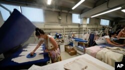 Workers iron clothes at the Cose di Maglia factory where the D.Exterior brand is produced, in Brescia, Italy, June 14, 2022.
