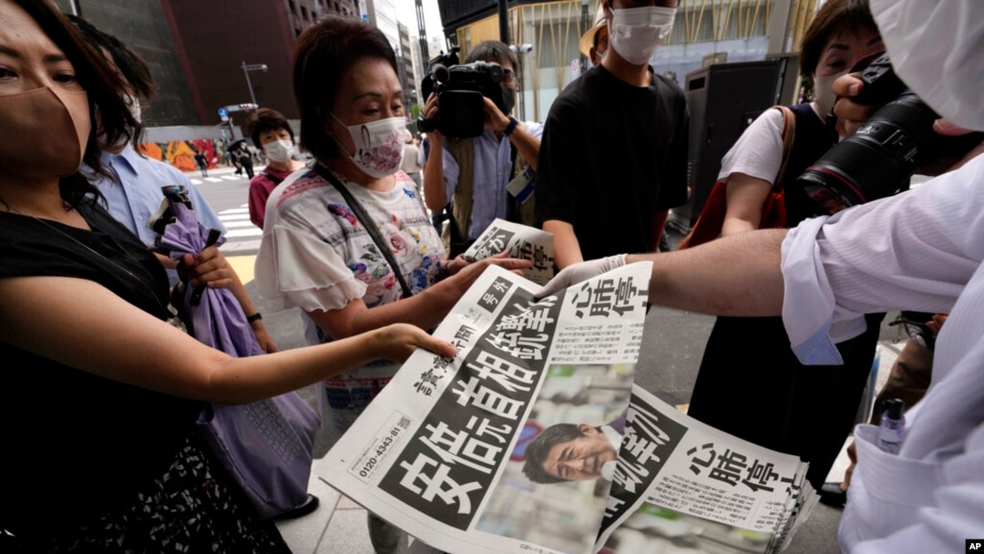 An employee distributes extra editions of the Yomiuri Shimbun newspaper reporting on Japan's former Prime Minister Shinzo Abe was shot, July 8, 2022, in Tokyo.