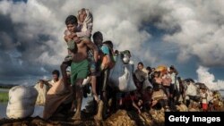 FILE - Rohingya refugees fleeing Myanmar cross a muddy rice field in Palang Khali, Bangladesh, in October 2017. (IWMF/Paula Bronstein)