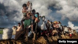 FILE - Rohingya refugees fleeing Myanmar cross a muddy rice field in Palang Khali, Bangladesh, in October 2017. (IWMF/Paula Bronstein)