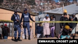 FILE: A relative of one of the 14 victims shot dead in a tavern in Soweto reacts next to the crime scene in Soweto on July 10, 2022. 